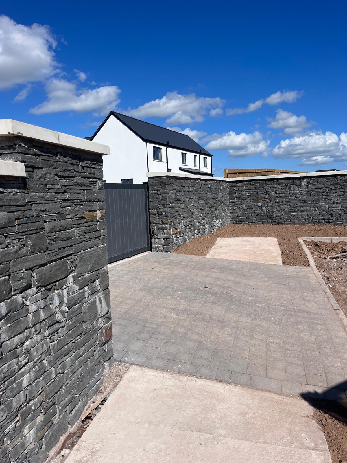 Completed RWC Landscapes garden in Cork with natural stone walls and a neatly paved patio